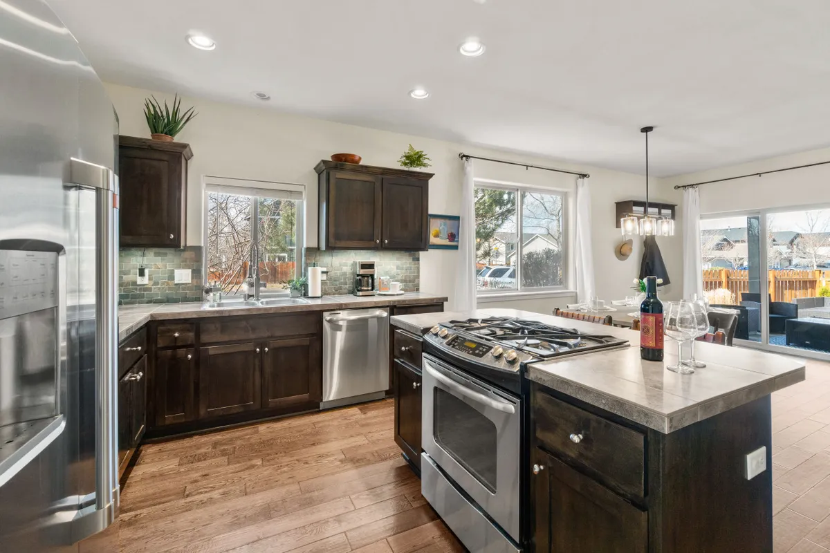 A bright, open kitchen and dining area with a kitchen island, stainless steel appliances, large windows, and a dining table. The space is filled with natural light and connects seamlessly to the living area, offering both function and style.